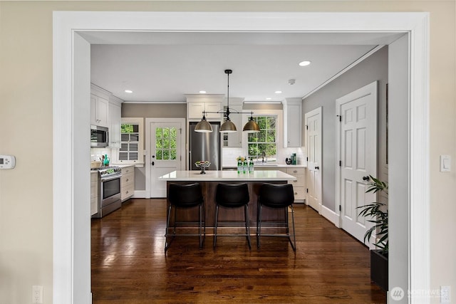 4404 Montana Cir W, Seattle, WA 98199 - kitchen with appliances with stainless steel finishes, light countertops, white cabinets, tasteful backsplash, and ornamental molding