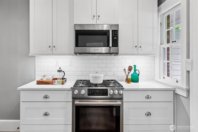4404 Montana Cir W, Seattle, WA 98199 - kitchen with appliances with stainless steel finishes, backsplash, and white cabinetry