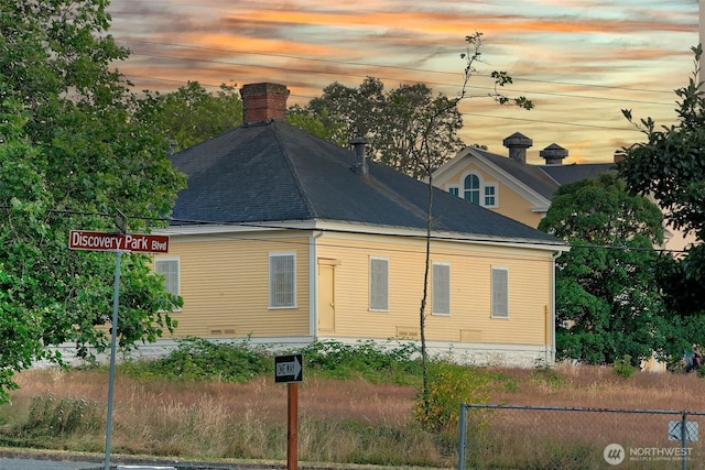 4404 Montana Cir W, Seattle, WA 98199 - property exterior at dusk featuring fence, a chimney, and a shingled roof