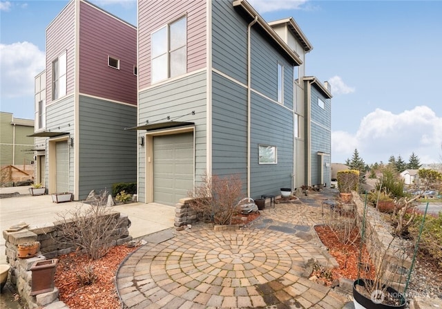 back of property featuring a garage and concrete driveway