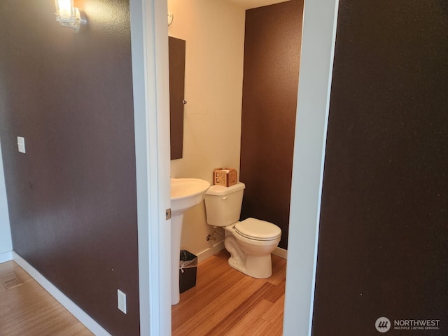bathroom with wood finished floors, toilet, and baseboards