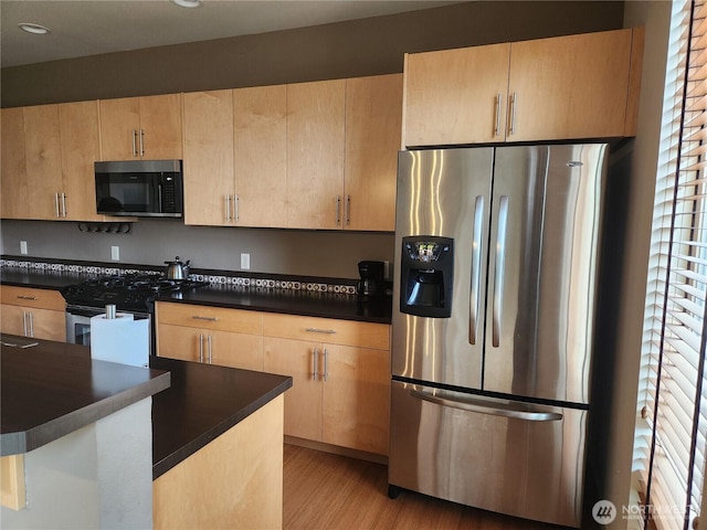 kitchen with stainless steel appliances, light brown cabinetry, dark countertops, plenty of natural light, and recessed lighting