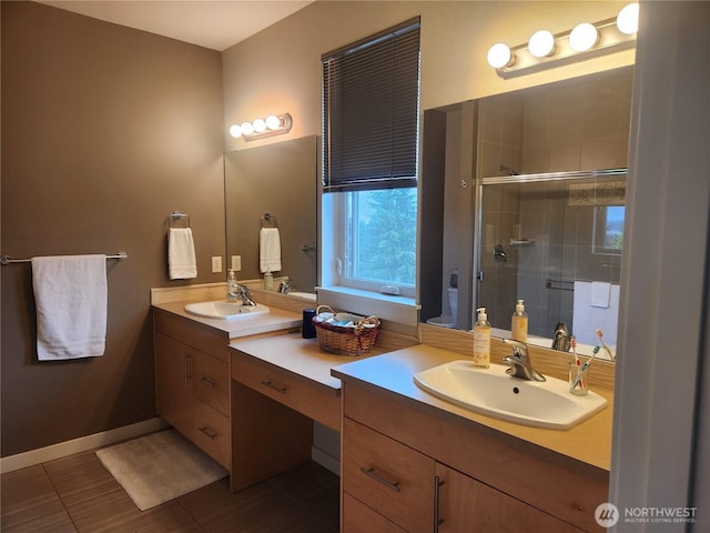 bathroom featuring a shower stall, double vanity, and baseboards