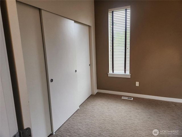 unfurnished bedroom featuring a closet, carpet floors, and baseboards