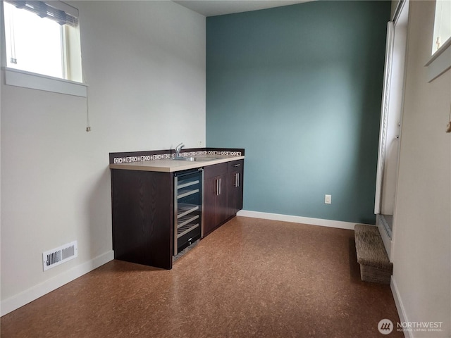 bar area with baseboards, wine cooler, and a sink