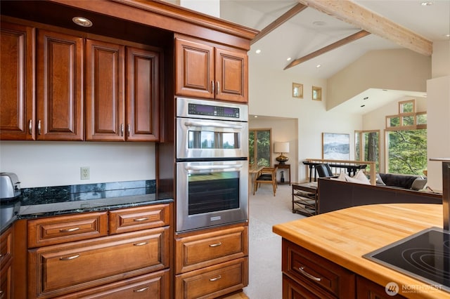 kitchen with black electric stovetop, stainless steel double oven, high vaulted ceiling, beamed ceiling, and wood counters