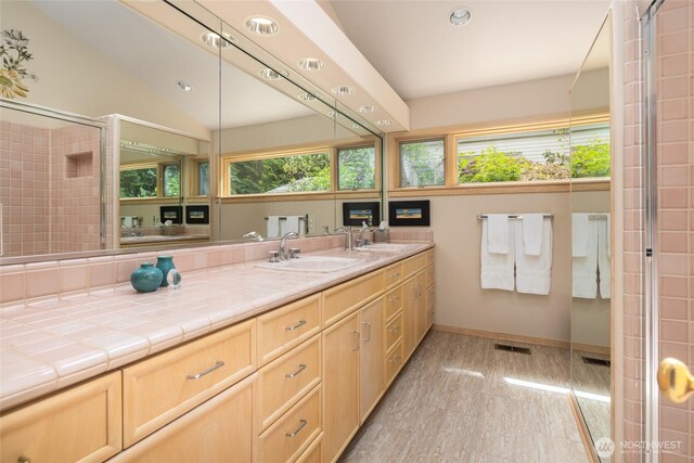 full bathroom featuring baseboards, vanity, recessed lighting, a tile shower, and vaulted ceiling