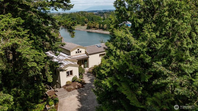 view from above of property with a nearby body of water and a heavily wooded area