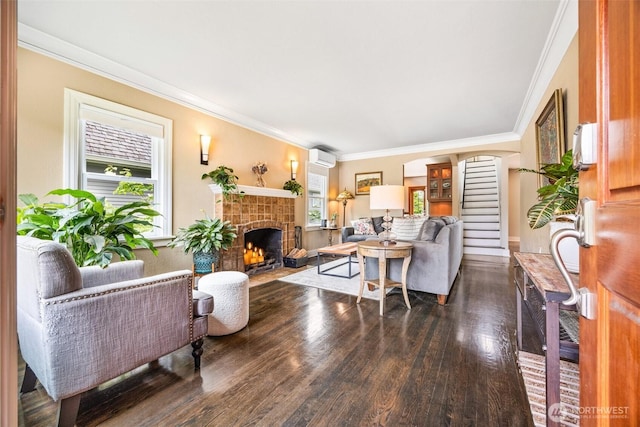 living room with wood finished floors, a tiled fireplace, ornamental molding, a wall mounted air conditioner, and arched walkways