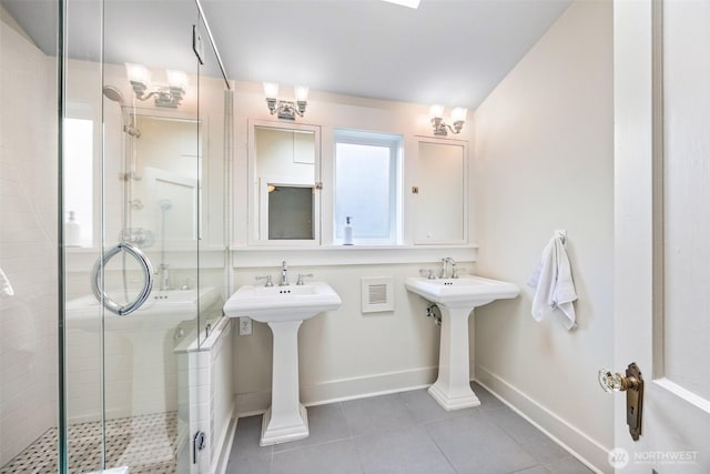 bathroom featuring a shower stall, baseboards, tile patterned flooring, and a sink