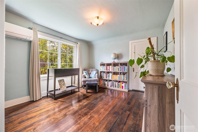 sitting room with a wall mounted AC, wood finished floors, and baseboards