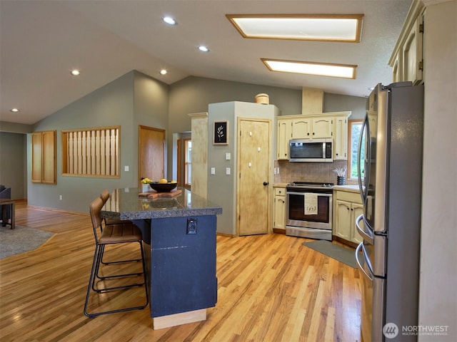 13708 401st Way, Amboy, WA 98601 - kitchen with stainless steel appliances, tile counters, lofted ceiling, light wood-type flooring, and a kitchen breakfast bar