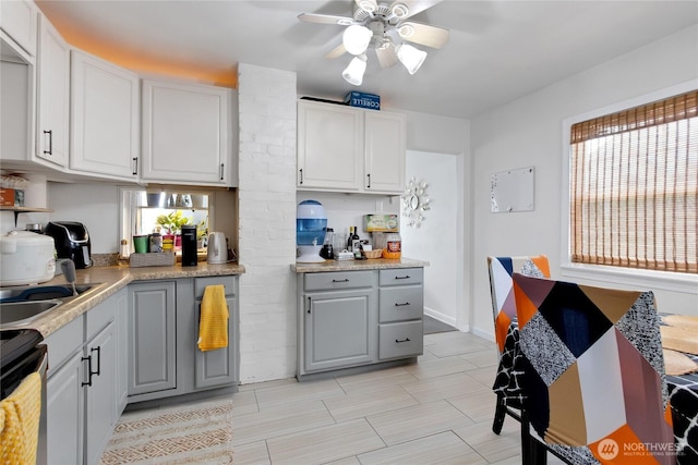 6928 S Cheyenne St, Tacoma, WA 98409 - kitchen with ceiling fan, gray cabinets, stove, light countertops, and white cabinetry