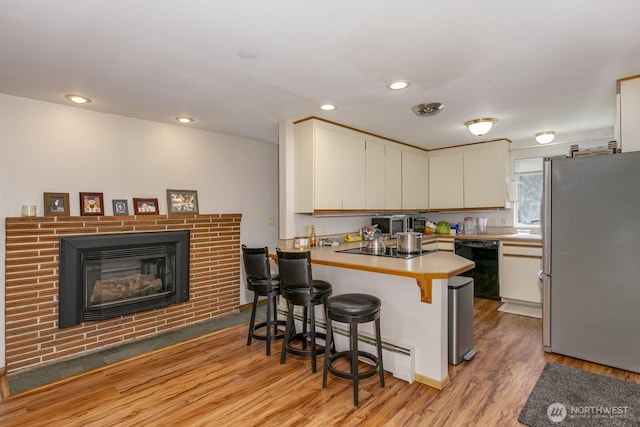 3822 Shelby Rd, Lynnwood, WA 98087 - kitchen with black appliances, a peninsula, light wood-type flooring, a kitchen bar, and white cabinetry