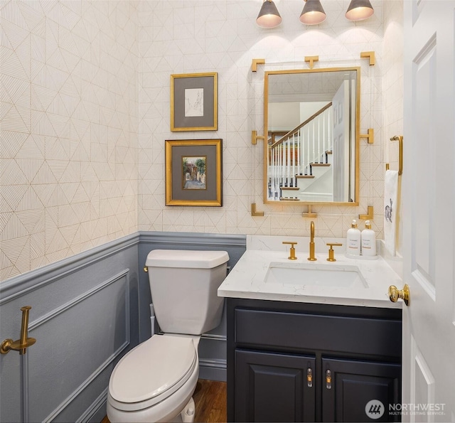 bathroom with toilet, vanity, tile walls, and wood finished floors