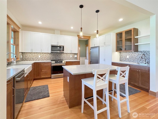 921 Chicken Coop Rd, Sequim, WA 98382 - kitchen featuring appliances with stainless steel finishes, a sink, a center island, decorative backsplash, and light wood-style floors
