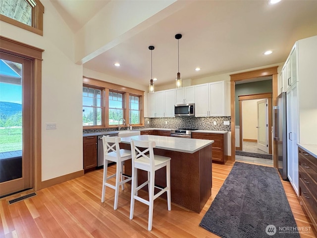 921 Chicken Coop Rd, Sequim, WA 98382 - kitchen with stainless steel appliances, light wood-style floors, tasteful backsplash, a kitchen island, and a kitchen breakfast bar