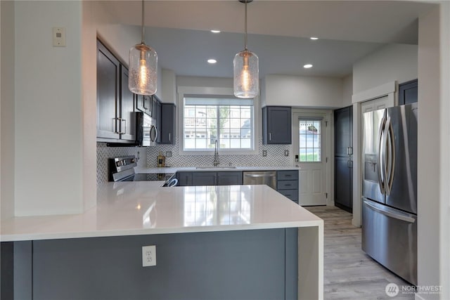 23120 SE Black Nugget Rd Unit A2, Issaquah, WA 98029 - kitchen with appliances with stainless steel finishes, a sink, decorative backsplash, light wood-style floors, and a peninsula