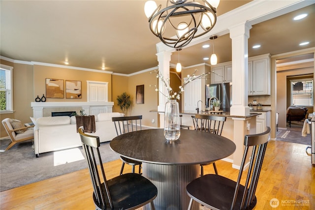 3212 Maplewood Cir NE, Tacoma, WA 98422 - dining space with decorative columns, light wood-style floors, ornamental molding, a fireplace, and a chandelier