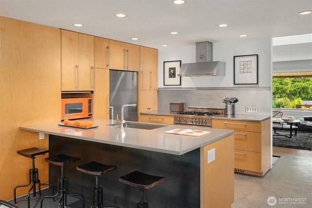 kitchen with appliances with stainless steel finishes, a sink, a kitchen bar, decorative backsplash, and recessed lighting