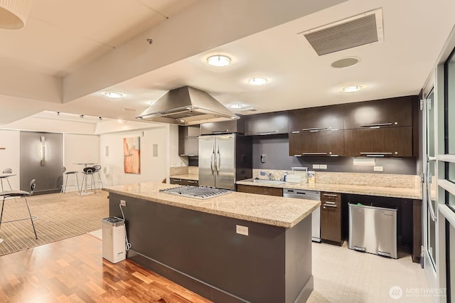 2911 2nd Ave Unit 513, Seattle, WA 98121 - kitchen with appliances with stainless steel finishes, a kitchen island, dark brown cabinets, light wood-style flooring, and modern cabinets