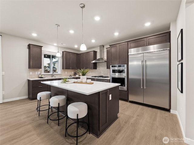 11455 SE 84th St Unit 43, Newcastle, WA 98056 - kitchen with appliances with stainless steel finishes, wall chimney exhaust hood, dark brown cabinetry, light wood-type flooring, and recessed lighting