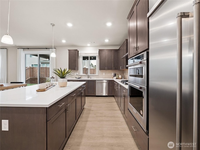 11455 SE 84th St Unit 43, Newcastle, WA 98056 - kitchen with appliances with stainless steel finishes, dark brown cabinets, light wood-style flooring, light countertops, and a sink