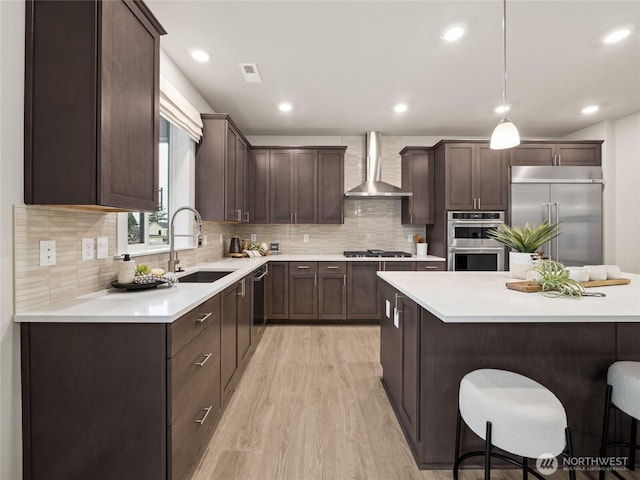 11455 SE 84th St Unit 43, Newcastle, WA 98056 - kitchen featuring wall chimney range hood, stainless steel appliances, a sink, a breakfast bar, and dark brown cabinetry