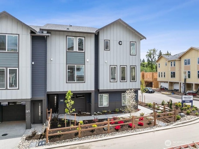 view of front of home featuring a garage, a fenced front yard, board and batten siding, and driveway