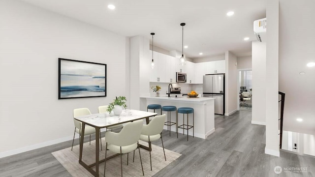 dining area with light wood-style flooring, baseboards, recessed lighting, and a wall mounted air conditioner