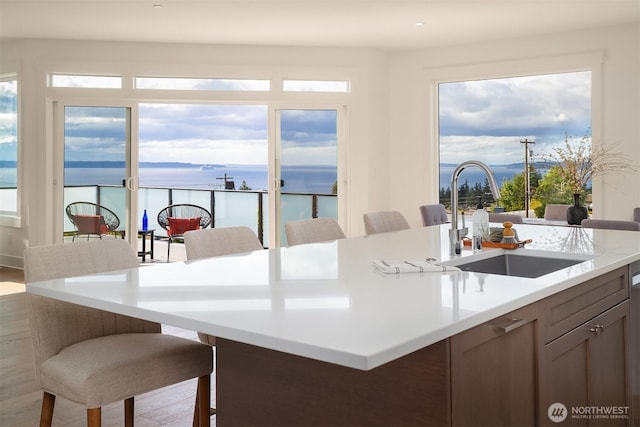 919 Cedar St, Edmonds, WA 98020 - kitchen featuring a sink, light countertops, wood finished floors, a breakfast bar, and a water view