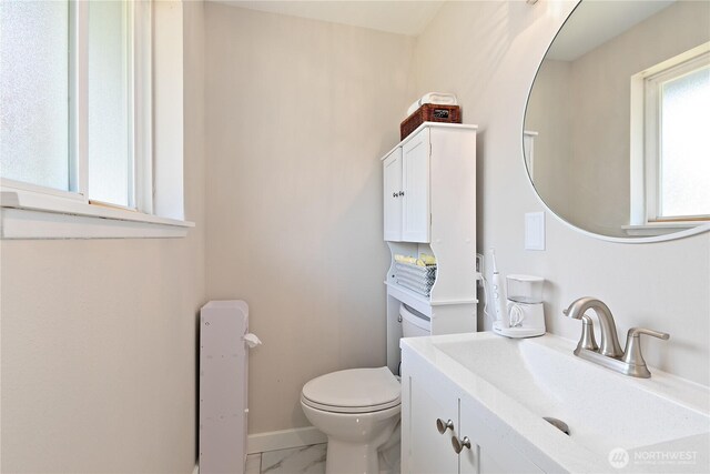 3415 Garden Ave N, Renton, WA 98056 - bathroom with vanity, toilet, marble look tile flooring, and baseboards