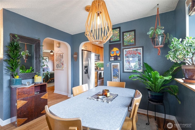 11008 2nd Ave S, Seattle, WA 98168 - dining space featuring arched walkways, light wood-style floors, a textured ceiling, and baseboards