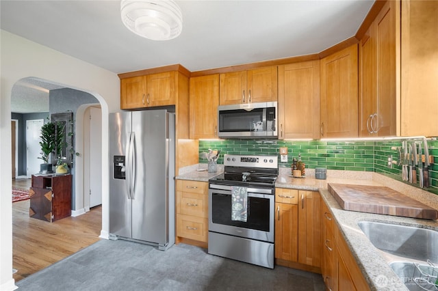11008 2nd Ave S, Seattle, WA 98168 - kitchen featuring stainless steel appliances, arched walkways, tasteful backsplash, and light stone counters