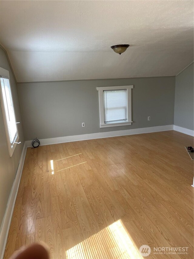 328 S Division St, Auburn, WA 98001 - empty room featuring wood finished floors, vaulted ceiling, a textured ceiling, and baseboards