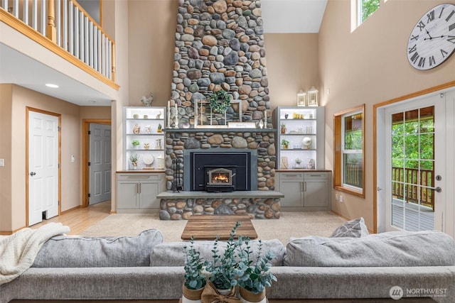 living room with a high ceiling, plenty of natural light, a stone fireplace, and baseboards