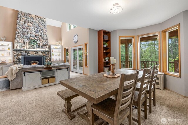 dining area featuring light carpet, a fireplace, and baseboards