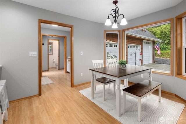dining area with a chandelier, light wood-style floors, and baseboards
