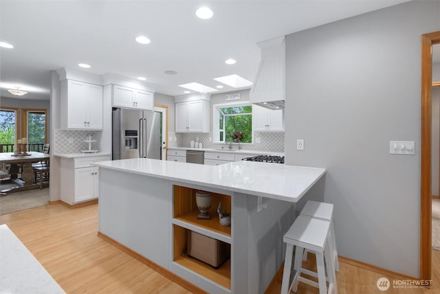 kitchen with stainless steel appliances, white cabinets, healthy amount of natural light, and recessed lighting