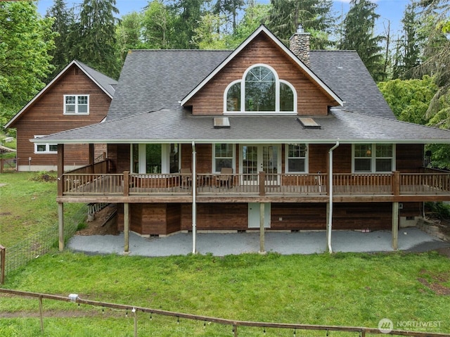 view of front of house with a shingled roof, a front yard, french doors, a chimney, and a patio area