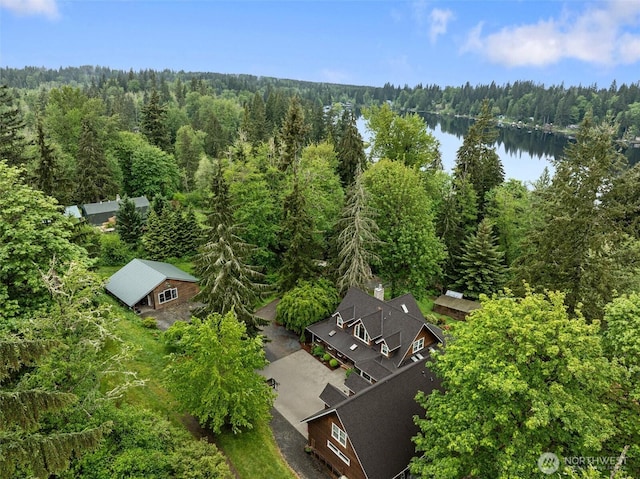 aerial view of property and surrounding area with a heavily wooded area and a large body of water