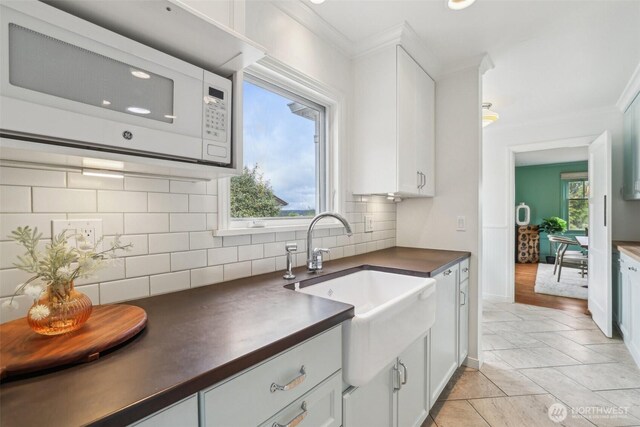 16255 38th Ave NE, Lake Forest Park, WA 98155 - kitchen with white microwave, dark countertops, ornamental molding, a sink, and decorative backsplash