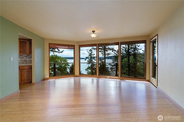 15127 Gibralter Rd, Anacortes, WA 98221 - empty room featuring light wood-type flooring, a water view, and baseboards