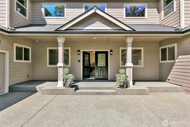 doorway to property featuring roof with shingles and covered porch