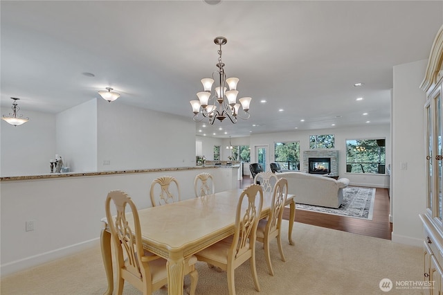 dining area featuring recessed lighting, a chandelier, light carpet, baseboards, and a glass covered fireplace
