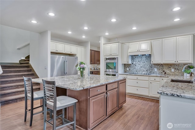 kitchen featuring a sink, stainless steel appliances, light wood-type flooring, white cabinets, and recessed lighting
