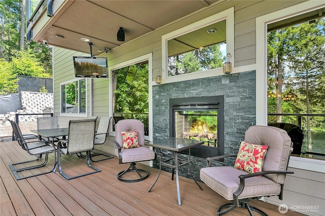 wooden terrace with a multi sided fireplace and outdoor dining area