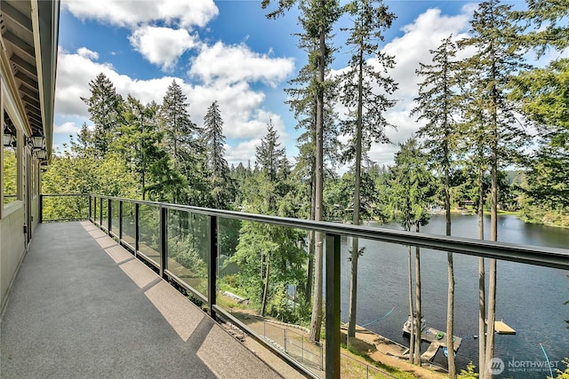 balcony with a water view and view of wooded area