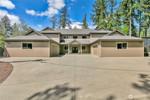 view of front of home featuring concrete driveway, an attached garage, roof with shingles, and french doors