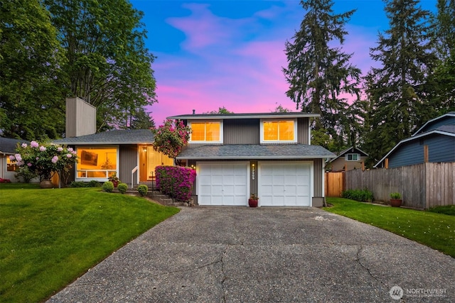 split level home with asphalt driveway, a garage, and a chimney